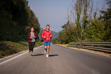 Image showing young couple jogging along a country road