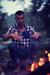 Image showing young friends relaxing around campfire