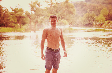 Image showing man with a bare torso splashing water