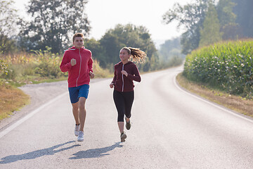 Image showing young couple jogging along a country road