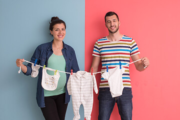 Image showing young couple holding baby bodysuits