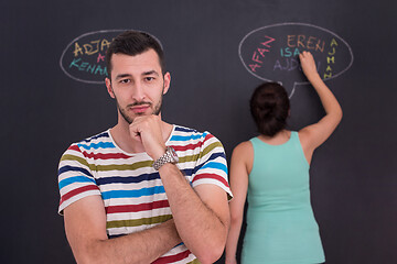 Image showing pregnant couple writing on a black chalkboard