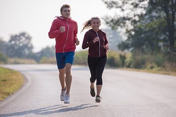 Image showing young couple jogging along a country road