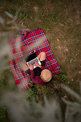 Image showing top view of man using a laptop computer under the tree