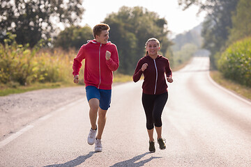 Image showing young couple jogging along a country road