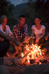 Image showing young friends relaxing around campfire