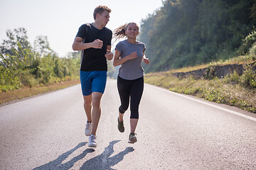 Image showing young couple jogging along a country road