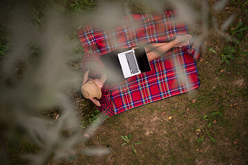 Image showing top view of man using a laptop computer under the tree