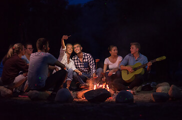 Image showing young friends relaxing around campfire