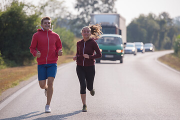 Image showing young couple jogging along a country road