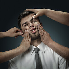 Image showing A young man surrounded by hands like his own thoughts