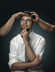 Image showing A young man surrounded by hands like his own thoughts