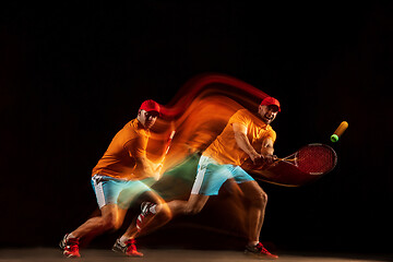 Image showing One caucasian man playing tennis on black background