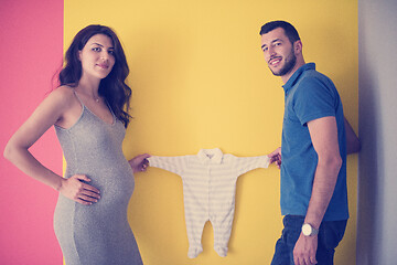 Image showing young couple holding baby bodysuits