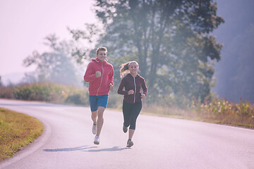 Image showing young couple jogging along a country road