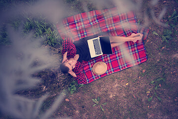 Image showing top view of man using a laptop computer under the tree