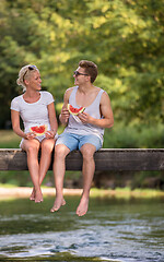 Image showing couple enjoying watermelon while sitting on the wooden bridge