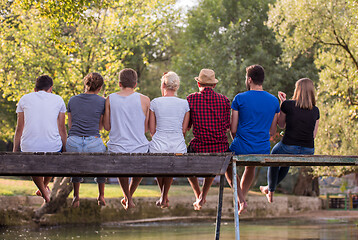 Image showing rear view of friends enjoying watermelon while sitting on the wo