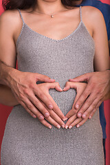 Image showing pregnant  couple showing heart with their hands