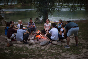 Image showing young friends relaxing around campfire