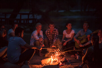 Image showing young friends relaxing around campfire