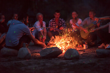 Image showing young friends relaxing around campfire