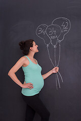 Image showing Portrait of pregnant woman in front of black chalkboard