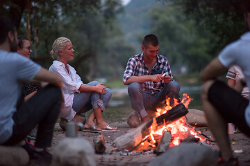 Image showing young friends relaxing around campfire