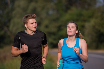 Image showing young couple jogging along a country road