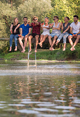 Image showing friends enjoying watermelon while sitting on the wooden bridge