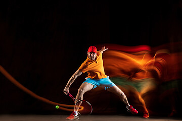 Image showing One caucasian man playing tennis on black background