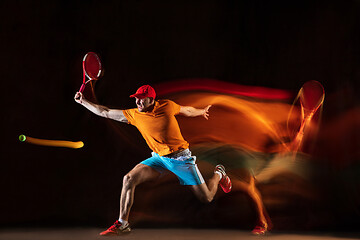 Image showing One caucasian man playing tennis on black background