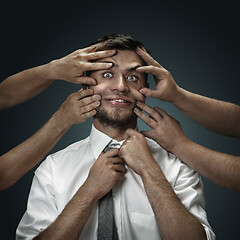 Image showing A young man surrounded by hands like his own thoughts