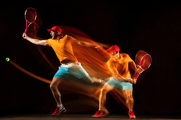 Image showing One caucasian man playing tennis on black background