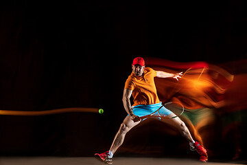 Image showing One caucasian man playing tennis on black background