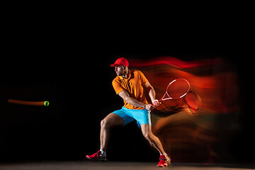 Image showing One caucasian man playing tennis on black background