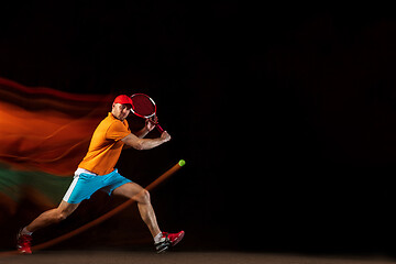 Image showing One caucasian man playing tennis on black background