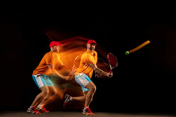 Image showing One caucasian man playing tennis on black background