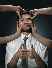 Image showing A young man surrounded by hands like his own thoughts