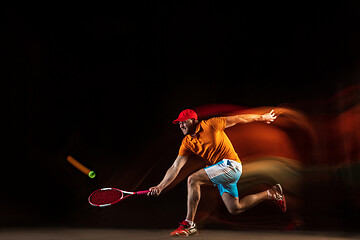 Image showing One caucasian man playing tennis on black background