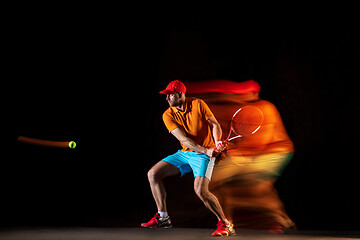 Image showing One caucasian man playing tennis on black background