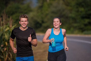 Image showing young couple jogging along a country road