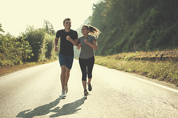 Image showing young couple jogging along a country road