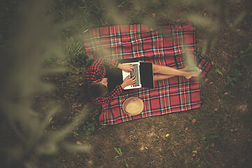 Image showing top view of man using a laptop computer under the tree