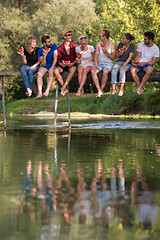 Image showing friends enjoying watermelon while sitting on the wooden bridge