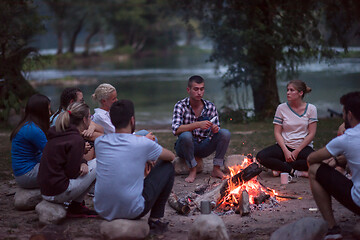 Image showing young friends relaxing around campfire