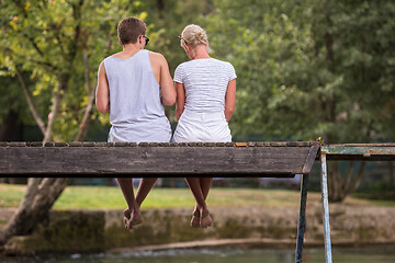 Image showing couple enjoying watermelon while sitting on the wooden bridge