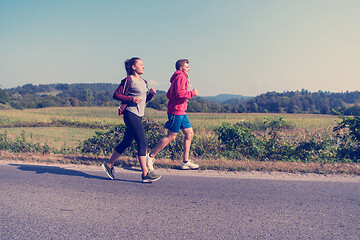 Image showing young couple jogging along a country road