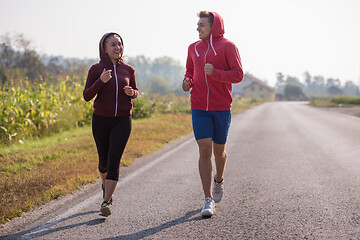 Image showing young couple jogging along a country road