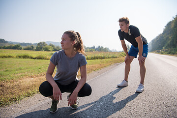 Image showing young couple warming up and stretching on a country road